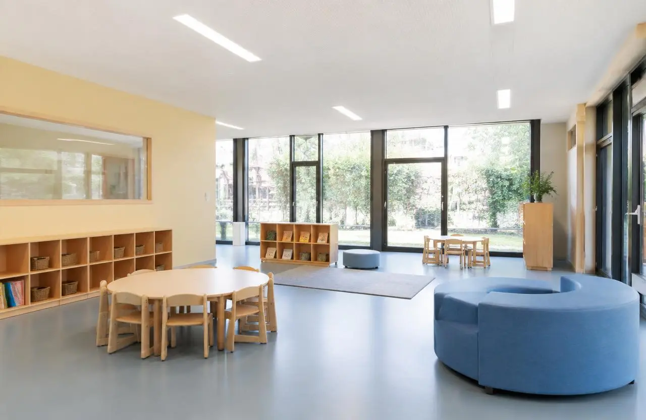 Illustrative childcare playroom with low cubbies and resilient flooring