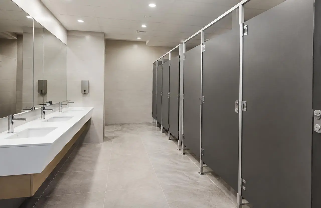 Illustrative commercial washroom with partitions, wall-hung sinks and porcelain tile